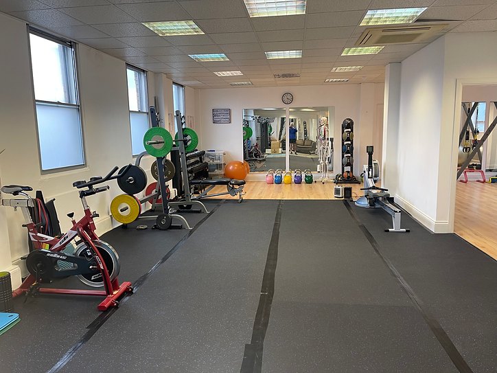 Training floor in the Reigate studio with barbell rack, weight plates, kettlebells and bike